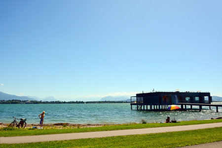On the sea pier is a large bungalow for vacationers, next to it two women are sunbathing on the beach. sea summer landscapeの写真素材