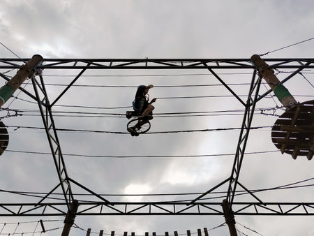 A teenage boy on a wheel rides on a suspension bridge in a rope amusement park. View from below on...