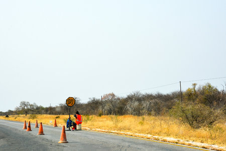 Repair crew workers sit on the side of the road near traffic cones to repair the road.