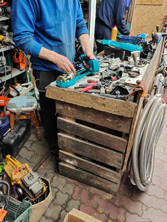 An amateur worker repairs an electrical appliance at an improvised workplace made of boxes. unknown...