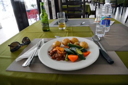 Cooked dish on a dinner plate on a restaurant table. There is also beer and mineral water. Side viewの写真素材