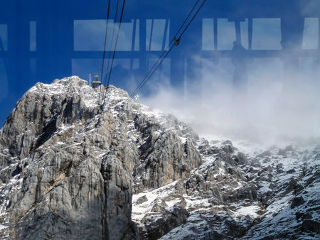 Rocky winter mountains covered with snow against a blue sky. View from the lift to the mountain through the glassの写真素材