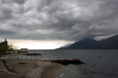 Sea evening shore of the cold sea bay. In the background are mountains with clouds hanging over themの写真素材