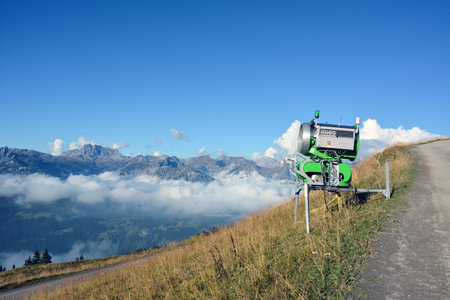 On a mountain slope above the clouds on a bright day, there is a cannon for making artificial snowの写真素材