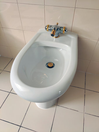 White bidet in the toilet. Ceramic tiles on the walls. An example of the decor and interior of a bathroom or toiletの写真素材