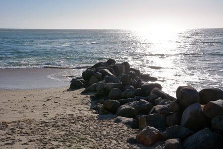 A pile of stones is piled up on the sea beach in front of the breakwater to protect against storm waves. Natural tourist landscapeの写真素材