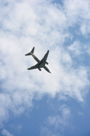 A passenger plane flies high in the blue sky with light clouds. Passenger transportation and airlinesの写真素材