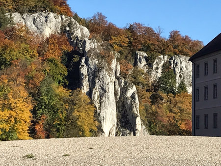 Stone rocks are overgrown with colorful autumn trees. Under part of the house can be seen through the rock. Natural scenic landscapeの写真素材