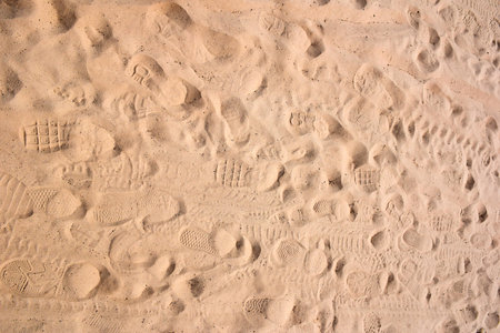 On the sand there are various shoe prints of different shapes all over the background. View from aboveの写真素材