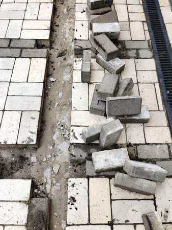 A view of the construction of a tiled stone sidewalk with a drainage ebb. Infrastructure construction site. Side viewの写真素材