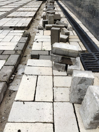 A view of the construction of a tiled stone sidewalk with a drainage ebb. Infrastructure...