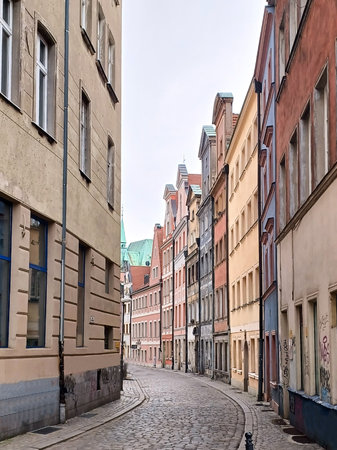 A picturesque empty narrow street of an old Italian town with cobblestones and facades of various buildings in perspectiveの写真素材