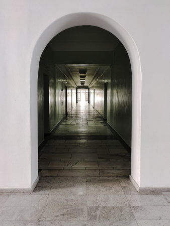 Entrance to a dark arched corridor in perspective. A bright light shines at the end. The floor is tiledの写真素材