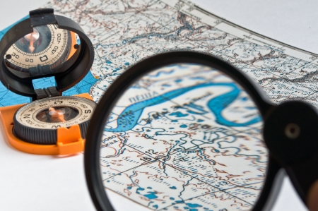 Compass in the orange casing and with the mirror cover is on the topographic map.の写真素材