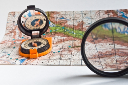 Compass in the orange casing and with the mirror cover is on the topographic map.の写真素材