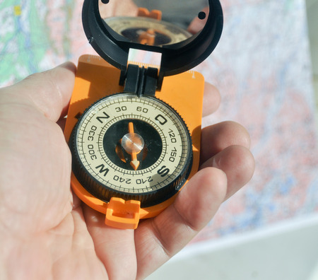 The compass in his hand. Black compass with the lid open and mirror lies on the palm.の写真素材