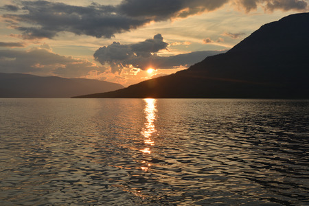 Sunset at Dog lake, Putorana plateau. The sun sets over the mountain and reflects in the water of the lake.の写真素材