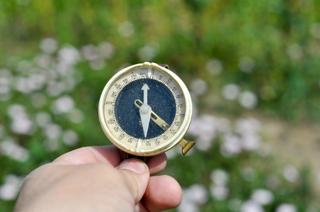 The compass in his hand. Magnetic compass in hand on the green meadows.の写真素材