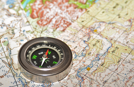 On a few maps is the magnetic compass. Compass laying on a topographic map.の写真素材