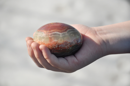 Easter egg made of Jasper lies in the hand and lit by the rays of the sun.の写真素材