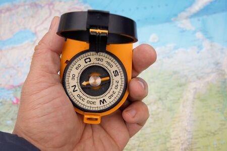 Compass in hand on a map background. Help not to get lost while traveling.