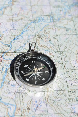 Magnetic compass and map. Tools that help you not to get lost on the ground.の写真素材