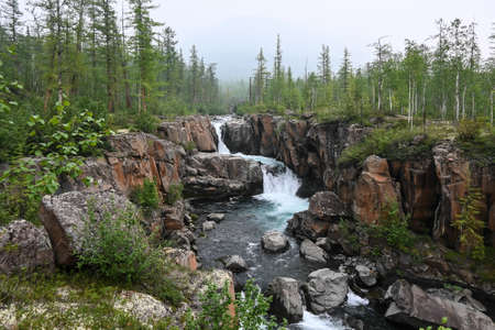 Putorana Plateau, a waterfall on the Grayling Stream. Mountain stream on a cloudy day.の写真素材