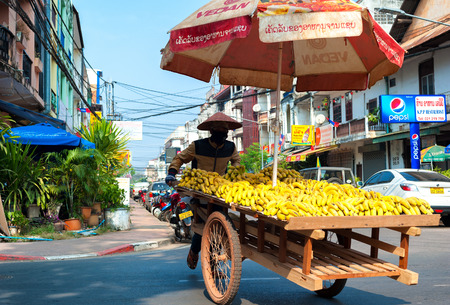 VIENTIANE, LAOS - 11 DEC,2013: Unidentified street vendor sells bananas in downtown of Laotian capital. The popularity of Laos as tourist travel destination increasing a lotのeditorial素材