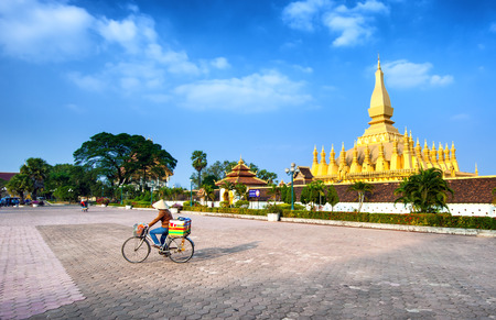 VIENTIANE, LAOS - 11 DEC,2013: Unidentified local woman on the bicycle on the square near golden pagoda wat Phra That Luang in Vientiane. Popular travel destinationのeditorial素材