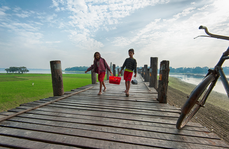 MANDALAY, MYANMAR - JAN 19, 2014  Unidentified Burmese boy and girl crossing U Bein bridge  The teak bridge is under protection from Ministry of Culture of Burma as cultural heritage のeditorial素材