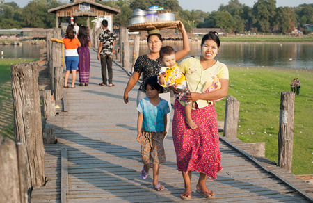 MANDALAY, MYANMAR - JAN 19, 2014  Unidentified local citizens of Amarapura crossing U Bein bridge located on Taungthaman Lake  Bridge is believed to be the oldest and longest teak bridge in the worldのeditorial素材