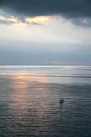 Calm evening sea with a yacht in front of a thunder-storm. Greece