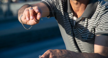 Freshly caught horse mackerel fish on a hook on a man's hand, side view.の写真素材