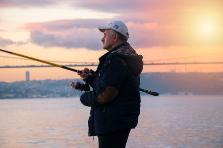 Fishing In A Wonderful Sunset. Fatih Sultan Mehmet Bridge and Fisherman. Fisherman is Fishing on the Bosphorus Beach on October 26, 2018 in Turkeyのeditorial素材