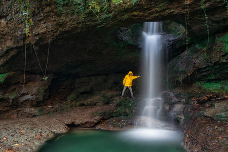 A man waterfall his hand (washes his hands) in the waterfall (water).