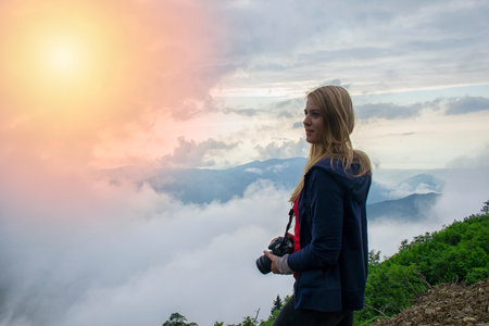A young girl photographing with a professional camera on a high plateau.の写真素材
