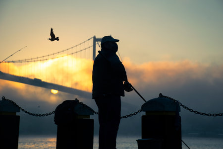A fisherman fishing with his fishing rod in the foggy Bosphorus. A foggy view from the July 15...
