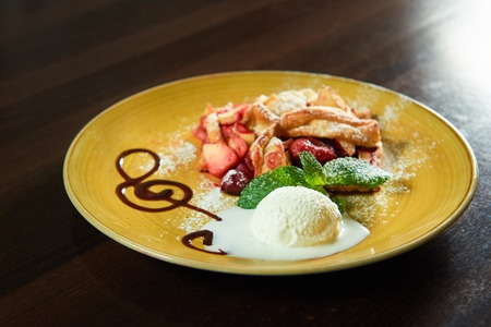 Pastry art. Closeup of a scoop of ice cream on a plate with a piece of fruit strudelの写真素材