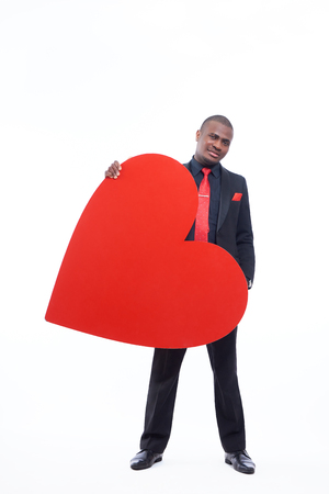 African man in suite holding big red heart.の写真素材