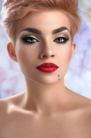 Gorgeous young red lipped woman posing over flower wall backgrouの写真素材