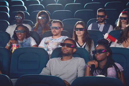 Africans and caucasians watching movie in 3d glasses.の写真素材