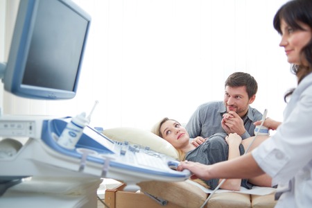 Loving couple attending doctor for pregnancy ultra sound proceduの写真素材