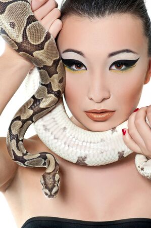 Beautiful Asian girl in a little black dress holding a snakeの写真素材