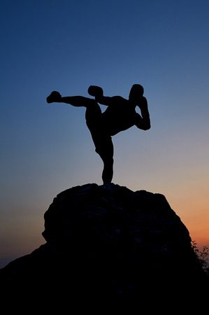 Dark silhouette of a muscular male boxer outdoors on sunsetの写真素材