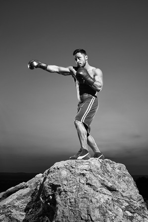 Monochrome shots of a fierce male boxer training outdoorsの写真素材
