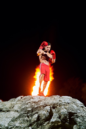 Boxing champion posing on top of a rock with fire burning on theの写真素材