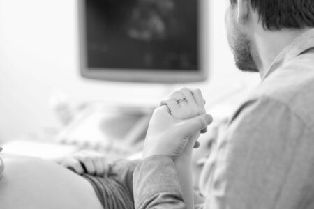 Young loving pregnant couple visiting doctor together monochrome
