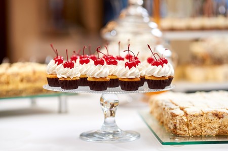 Plate full of cupcakes with cream and cherry on topの写真素材