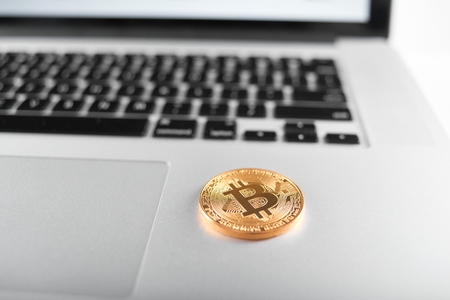 Golden bitcoins as main cryptocurrencies placed on silver laptop keyboard.の写真素材