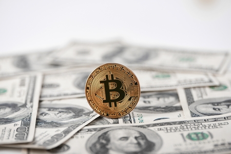 Golden bitcoin with hundred dollar banknotes on background.の写真素材